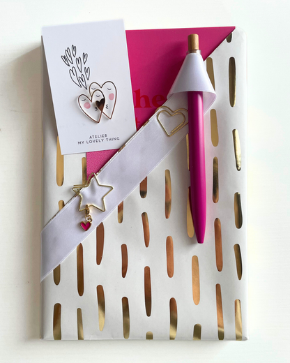 Decorative white holder with cut-out designs, pink pen, and card on a light background