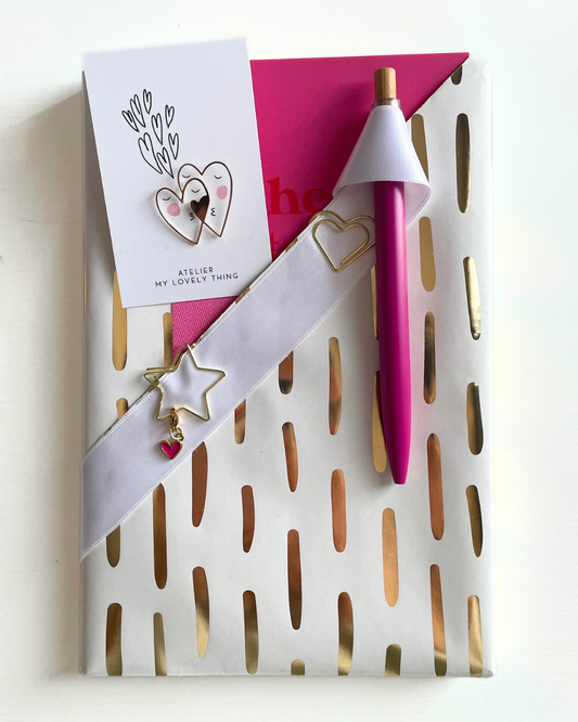 Decorative white holder with cut-out designs, pink pen, and card on a light background