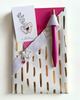 Decorative white holder with cut-out designs, pink pen, and card on a light background