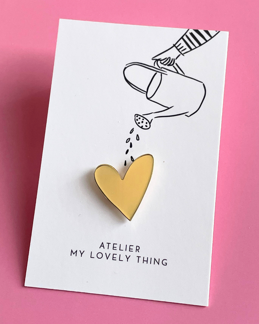 Decorative stationery set with pink pen, card, and gold heart-shaped clips on a white background