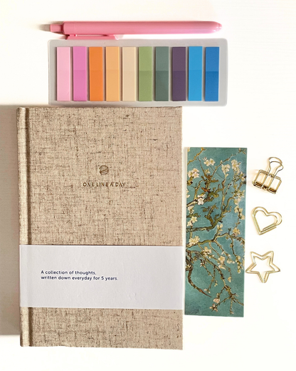 Journal with colorful bookmarks, a bookmark with floral design, and decorative clips on a light background.