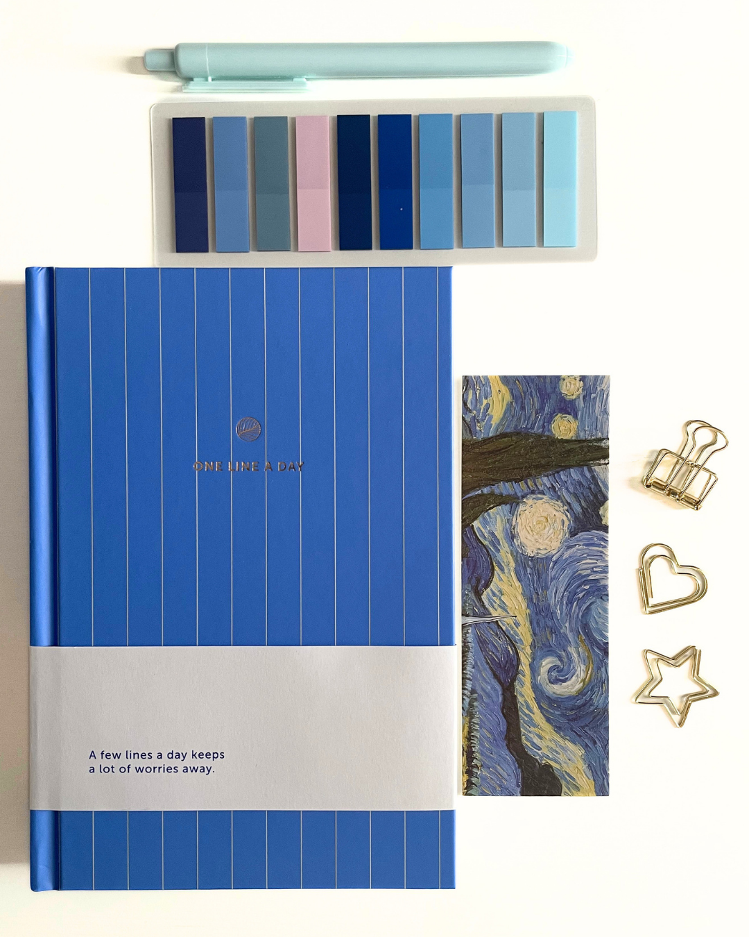 Blue notebook with white stripe, pen, color swatches, and decorative items on a textured surface