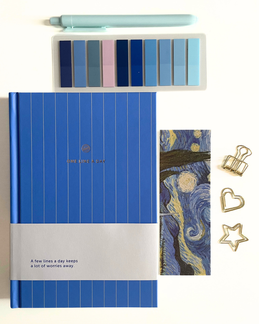 Blue notebook with white stripe, pen, color swatches, and decorative items on a textured surface