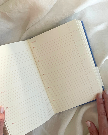 Open notebook with lined pages held by a person on a white fabric background