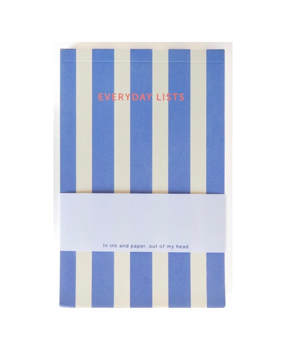 A notebook with vertical blue and cream stripes, featuring the title 'EVERYDAY LISTS' in coral text and a white paper band wrapped around the middle with the subtitle 'in ink and paper, out of my head'.