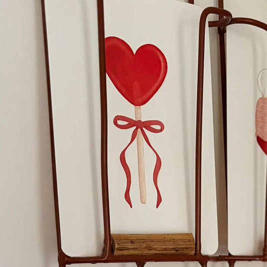 Red heart-shaped lollipop with a bow on a white background