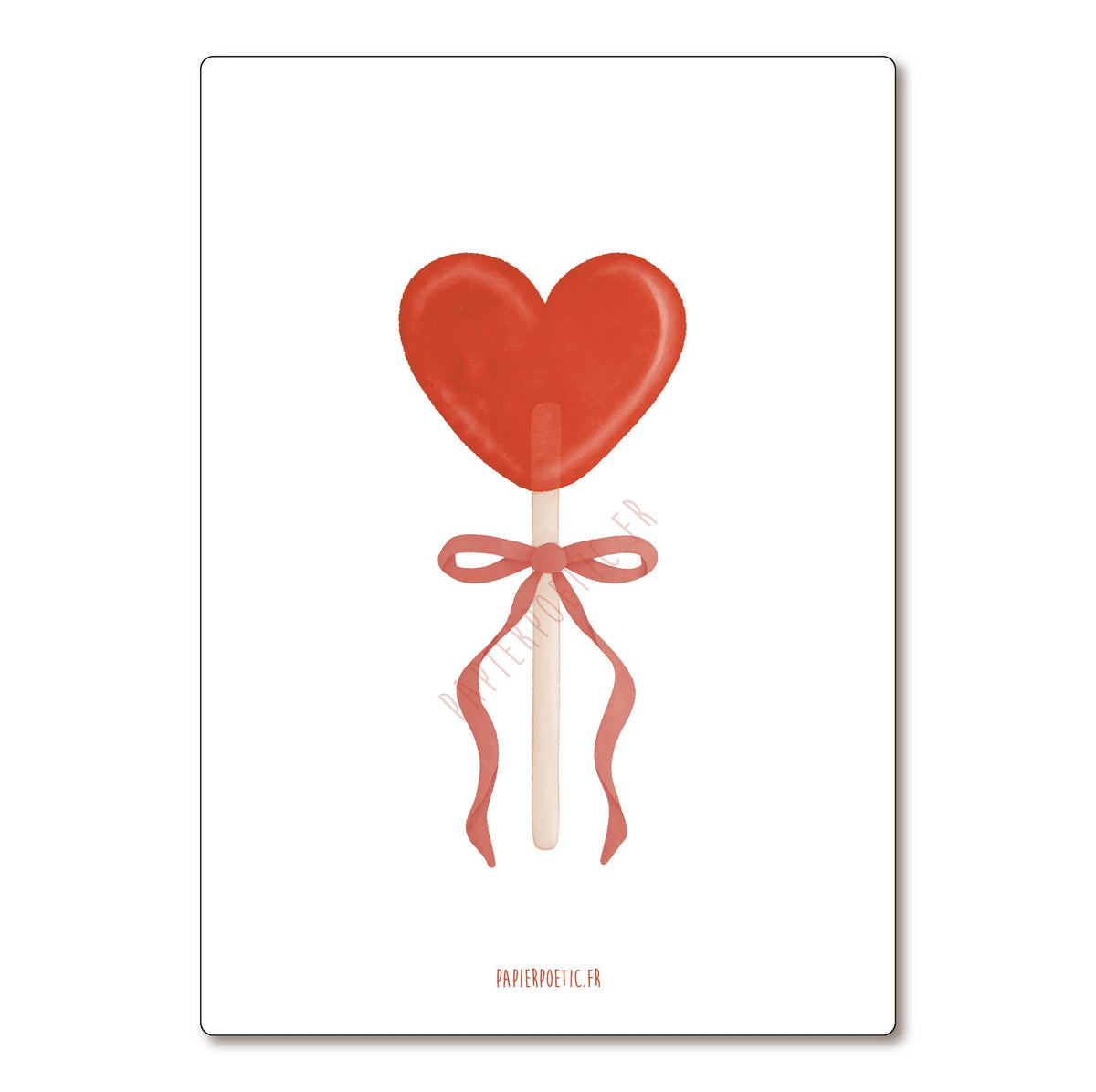Red heart-shaped lollipop with a bow on a white background