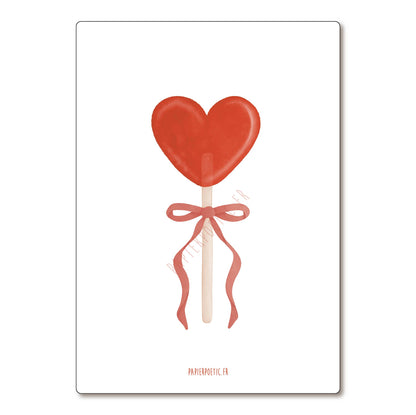 Red heart-shaped lollipop with a bow on a white background