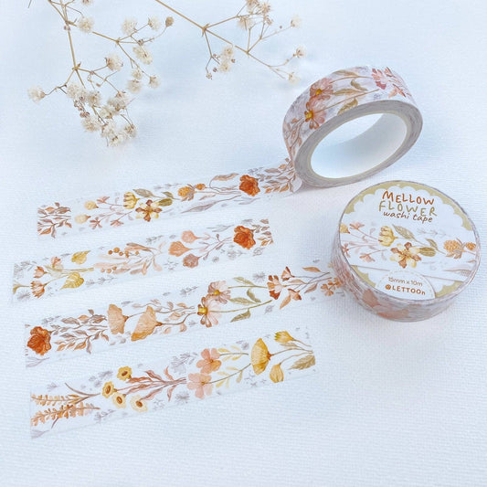 Four vertical strips of floral washi tape with a watercolor-style botanical pattern in muted orange, yellow, peach, and soft green on a white background. A roll of matching tape is partially visible at the bottom.