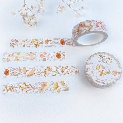 A roll of washi tape and several strips laid out on a white surface, featuring a delicate floral pattern in soft orange, yellow, and muted green tones. The round label on the tape roll reads 'MELLOW FLORAL washi tape' and shows the brand 'LETTOO'.