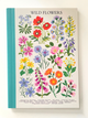 A hardcover book titled 'WILD FLLOWERS' with a cream cover printed with colorful botanical illustrations of various flowers, featuring a teal spine, photographed against a neutral off-white background.