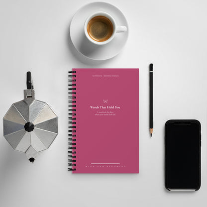 Pink notebook with a coffee cup, phone, and other items on a light gray background