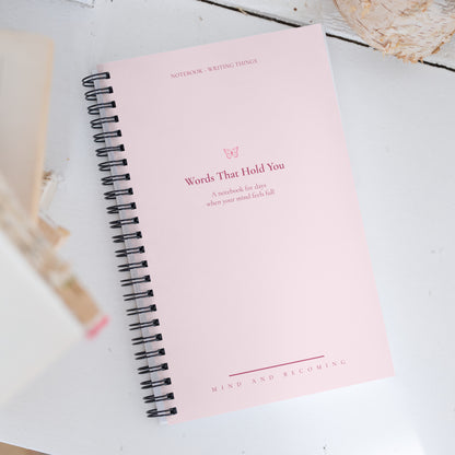 Pink notebook with text on a light wooden surface