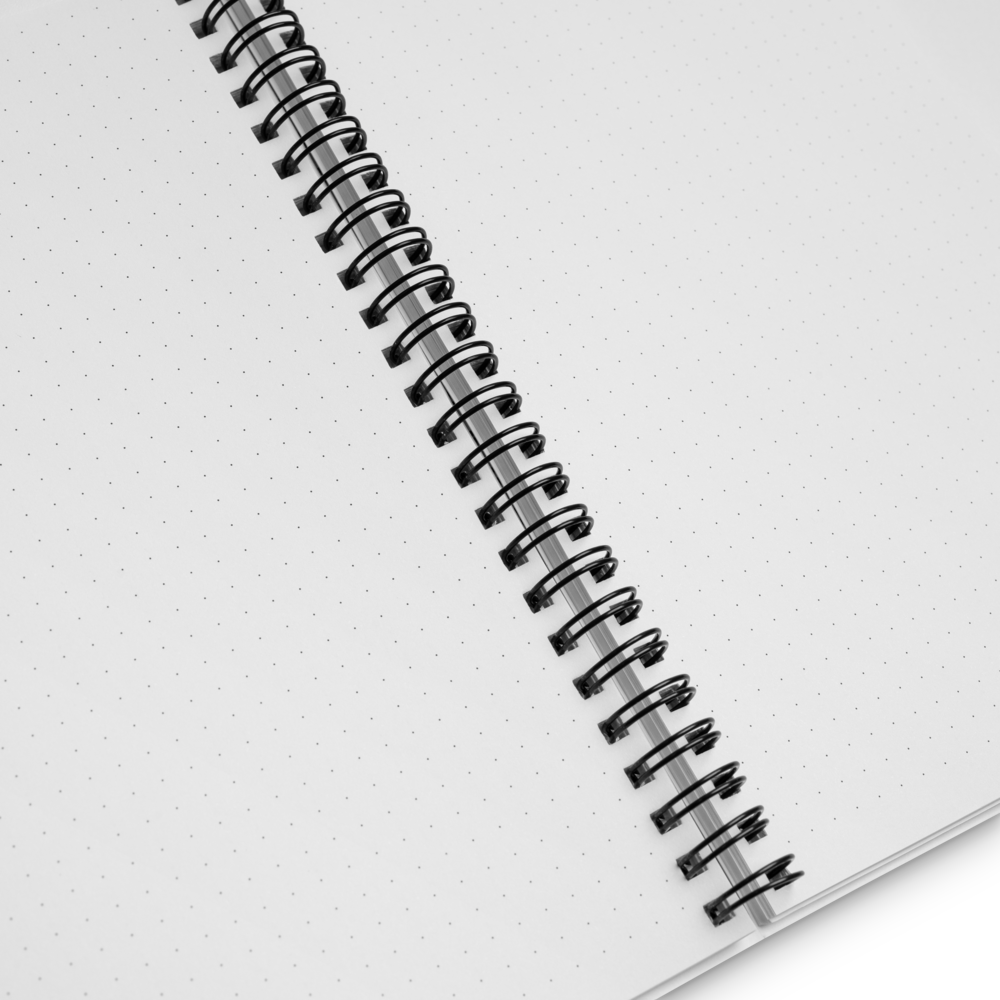 Close-up of a spiral-bound notebook with white pages on a light gray background