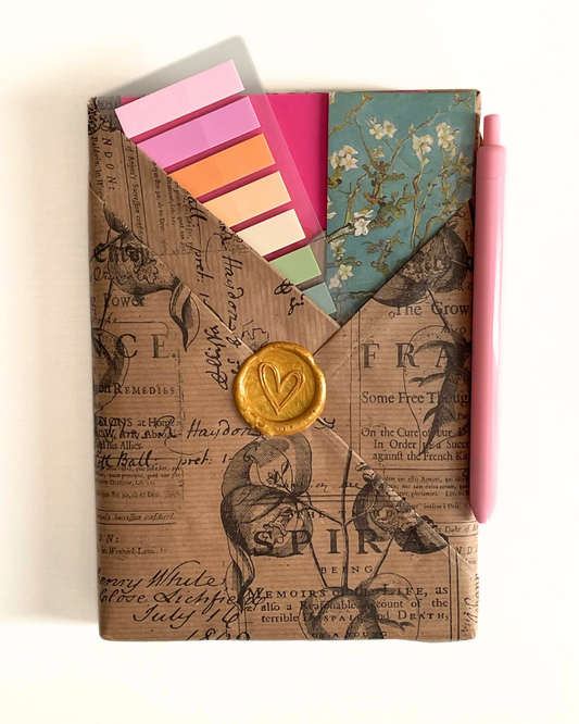 Journal with colorful bookmarks, a bookmark with floral design, and decorative clips on a light background.