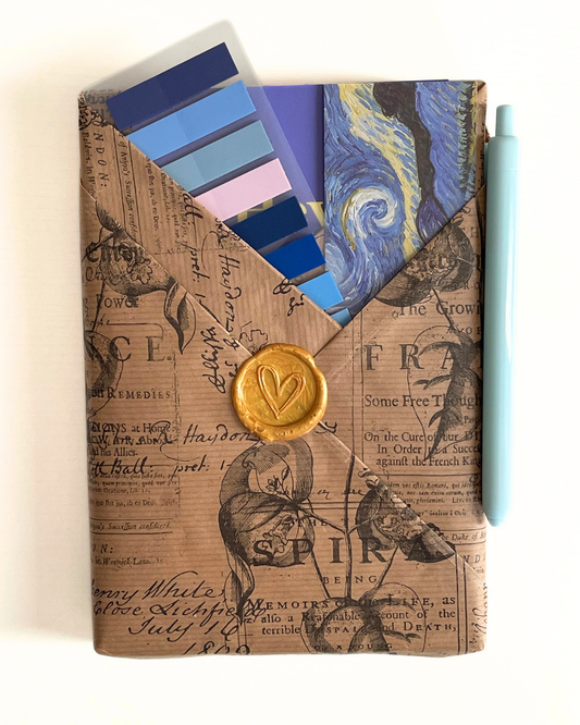 Blue notebook with white stripe, pen, color swatches, and decorative items on a textured surface