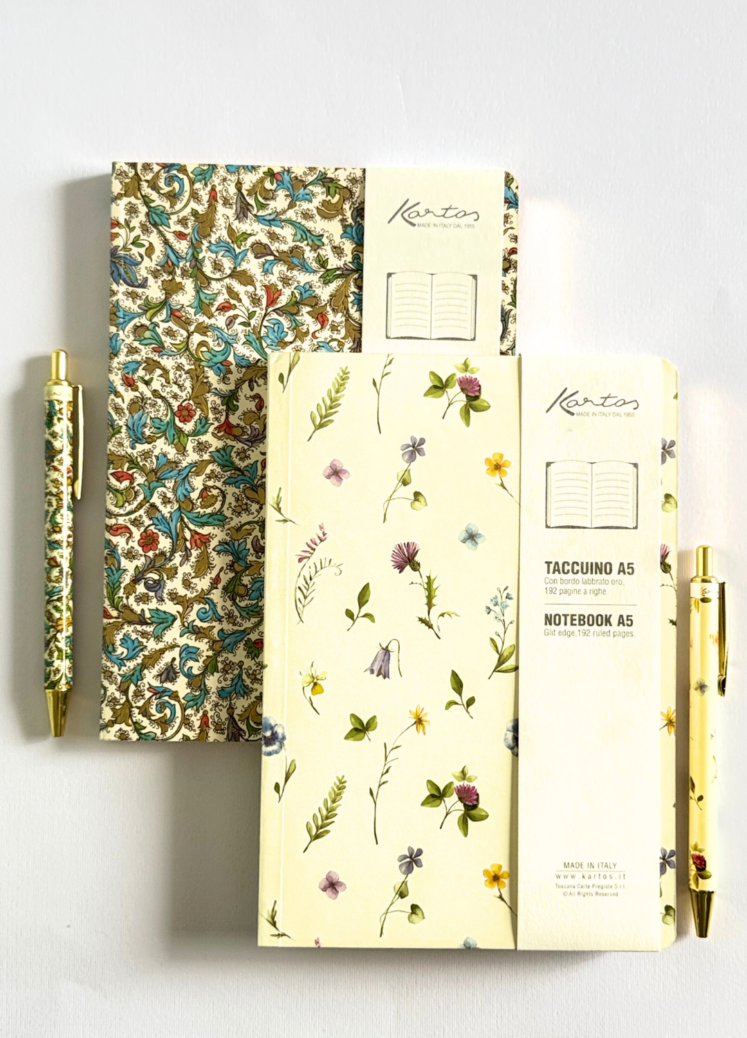 A Kanton stationery set featuring a floral notebook, a patterned notebook, a matching floral pen, and a patterned pen, arranged on a light gray background.